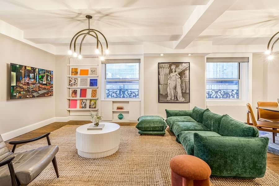 A spacious lobby with a green sofa, white coffee table, and artwork on the walls.